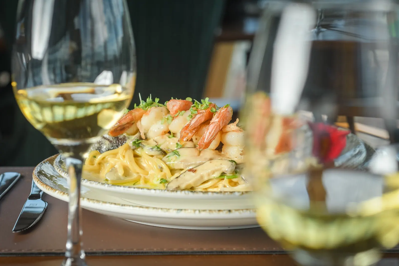 Espaguete com camarão e taça de vinho branco na mesa do almoço